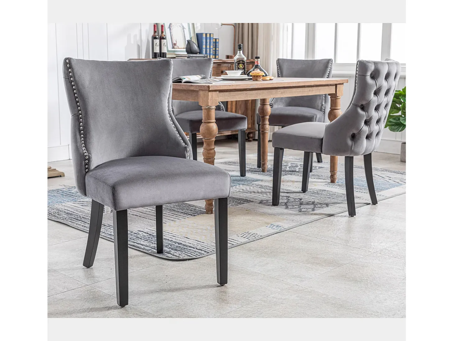 Juego de 4 sillas de terciopelo gris con patas de madera gris, botones decorativos y remaches plateados.
